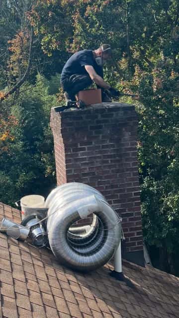 Sam fitting a chimney liner, with a coil of stainless steel liner on the roof.