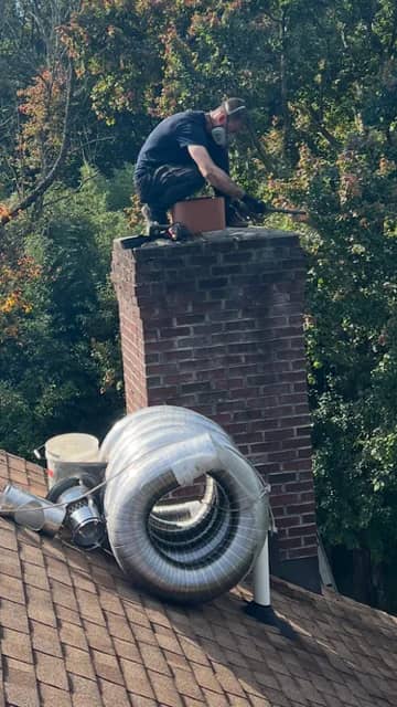 Sam fitting a chimney liner, with a coil of stainless steel liner on the roof.