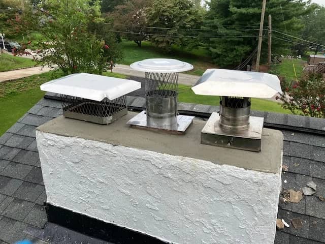 Light-colored chimney with three capped flue openings.